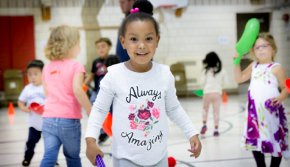 young children playing with toys inside a gymnasium