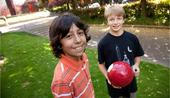 Two boys posing with a soccer ball 