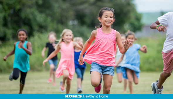A diverse group of young children run together playing outside.