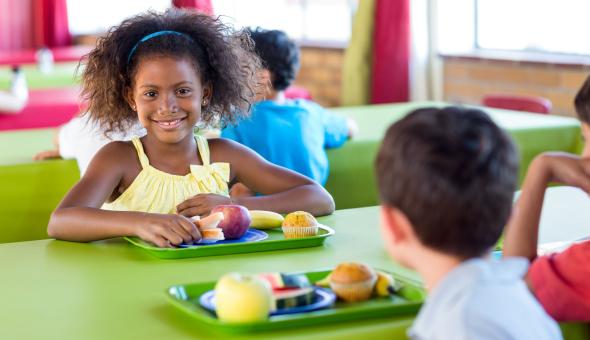 Smiling girl with classmates in cafeteria